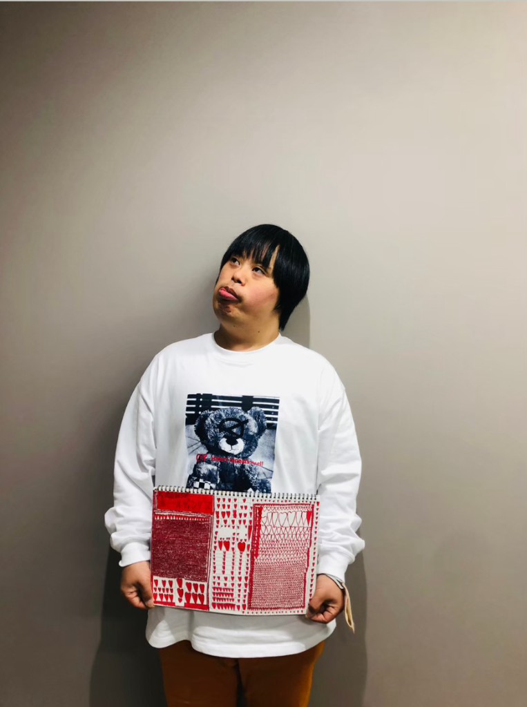 俊太朗さんがハートの模様を描いたスケッチブックを手に持つ写真